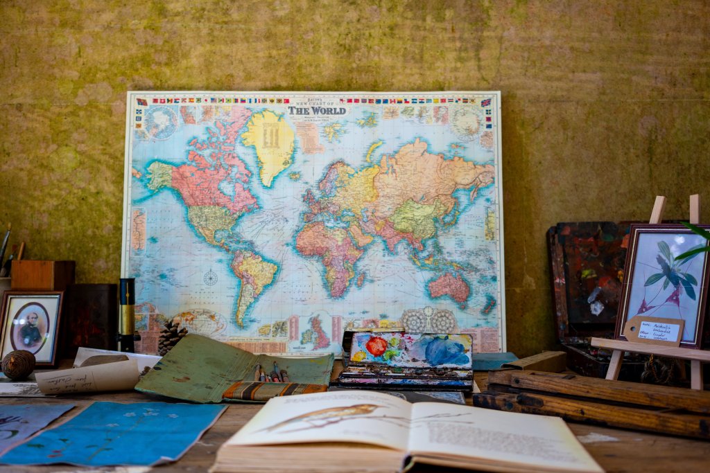 La traducción. Una mesa con mapa estilo vintage y algunos libros abiertos sobre ella delante de una pared en tonos ocres
